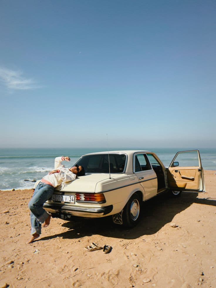 Traveler lying on a car by the ocean